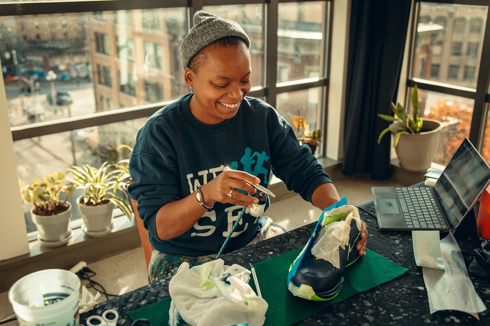An artist in her studio holding a painted Coach the Vote shoe.