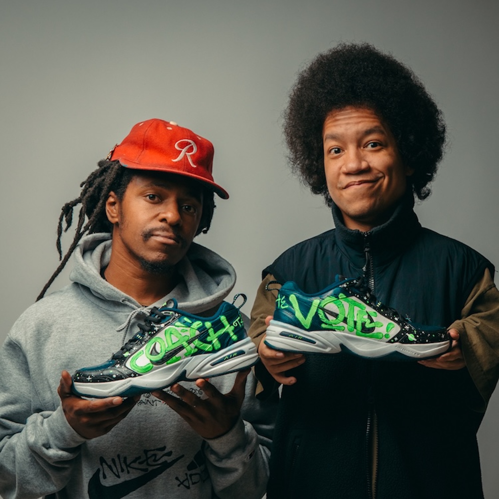 Two artists holding finished Coach the Vote shoes.