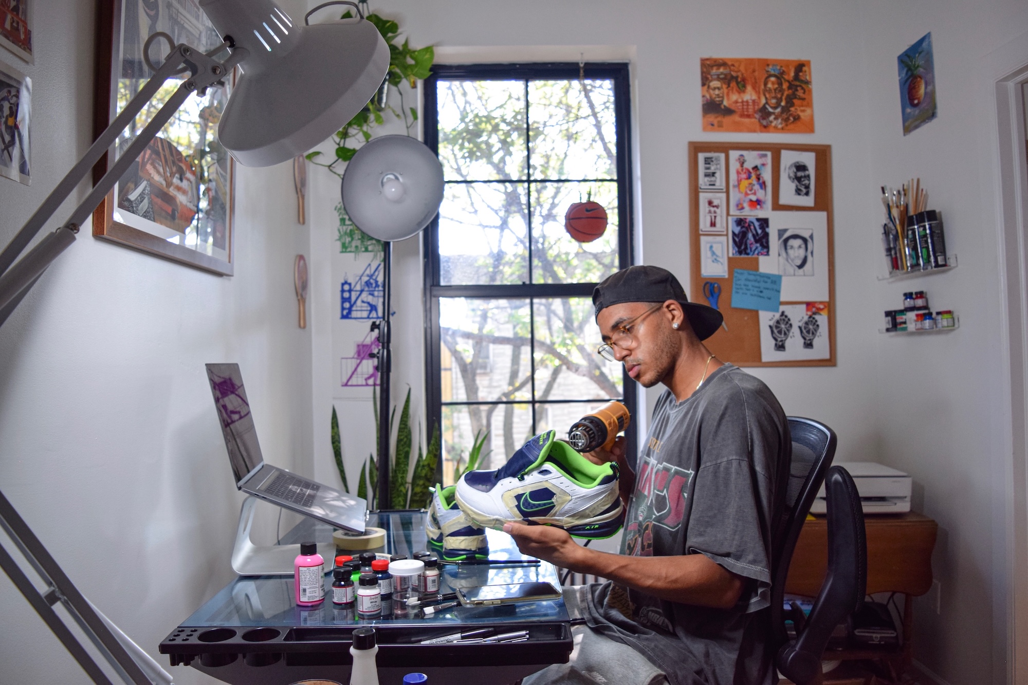 An artist heat-setting paint on a shoe at a desk.