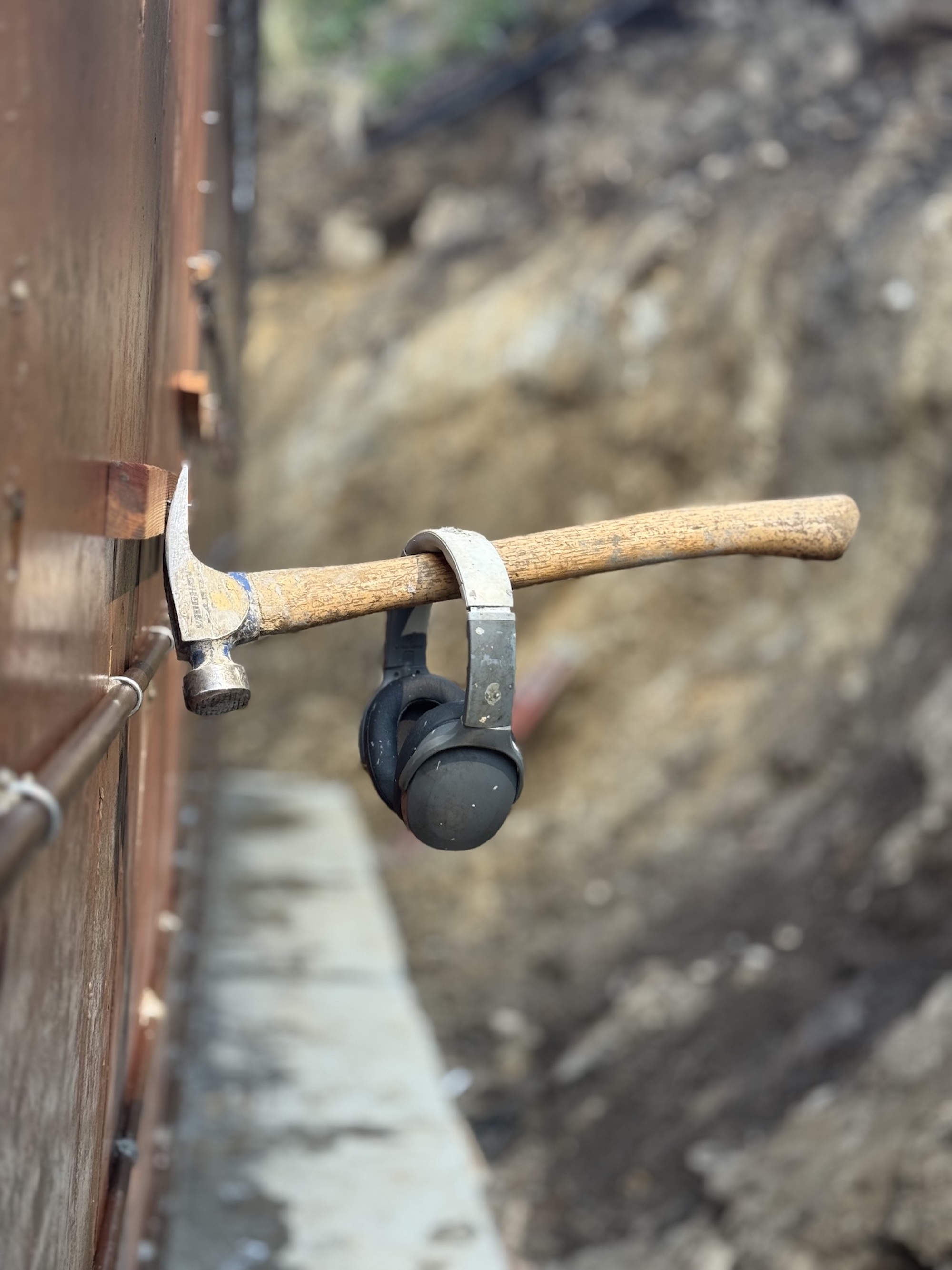 Headphones resting beside a hammer on a work surface