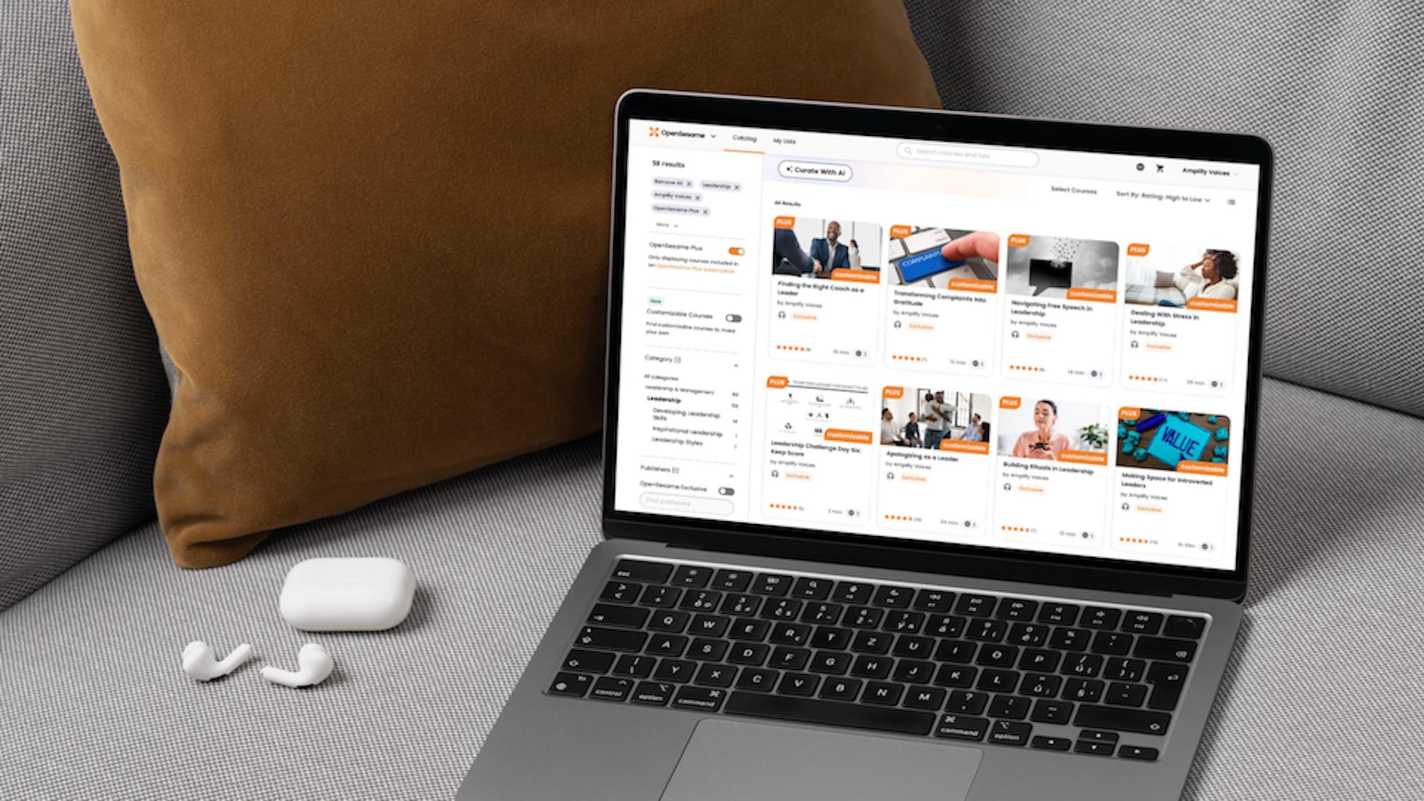 A laptop open on a couch showing the Amplify Voices catalog on the OpenSesame Plus platform.