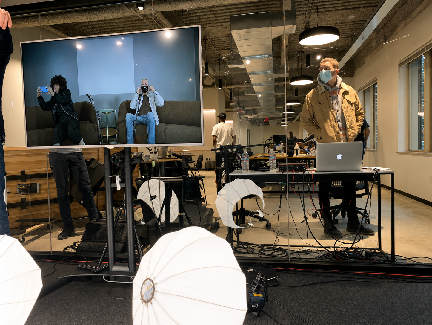 A masked crew working around lighting rigs and monitors during an early recording.